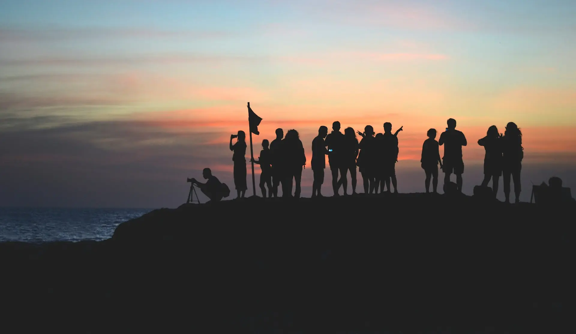 silhouette photography of people gathered together on cliff